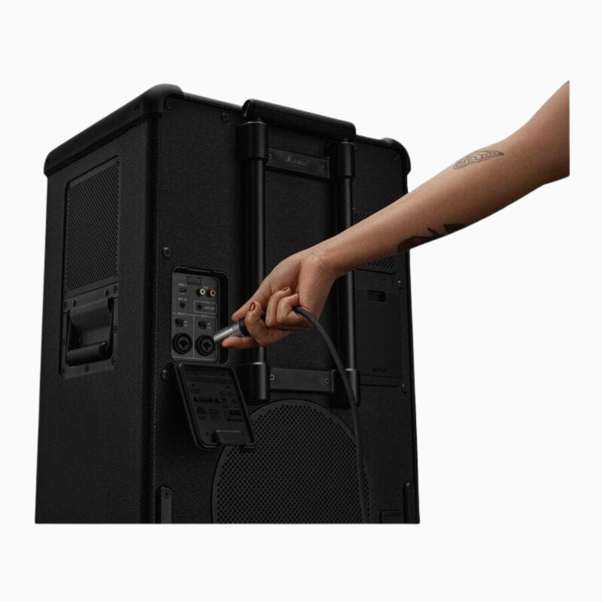 Person connecting a cable to a black speaker on a white background