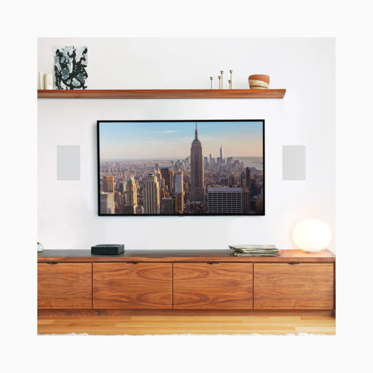 Wooden entertainment console with a television displaying a cityscape, flanked by speakers and decorative items.
