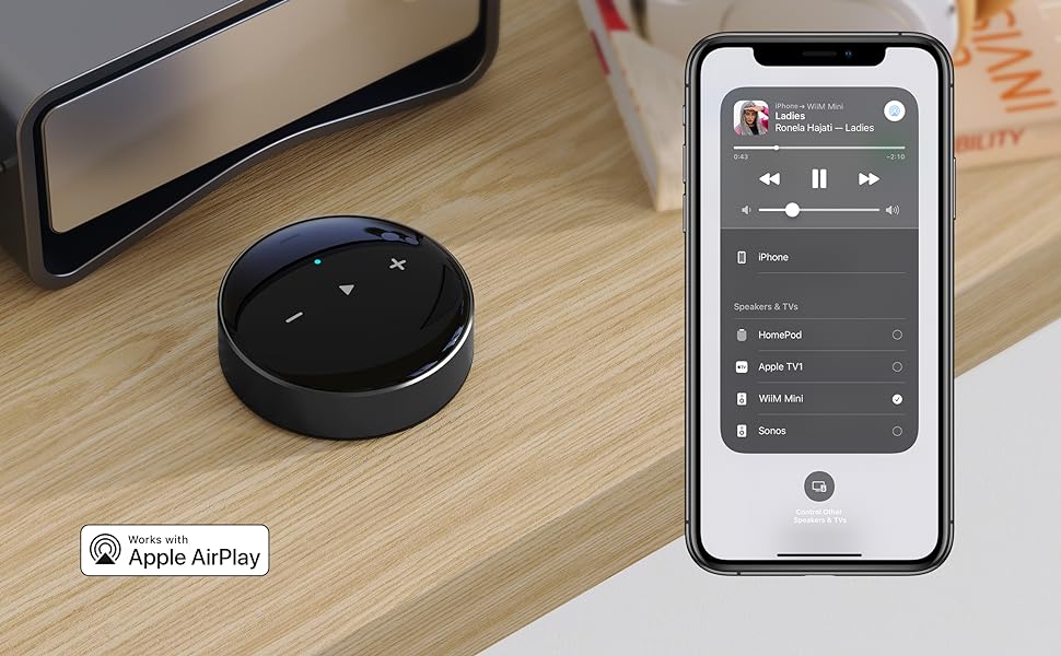 Black wireless speaker and smartphone with music app on a wooden surface, featuring Apple AirPlay logo.